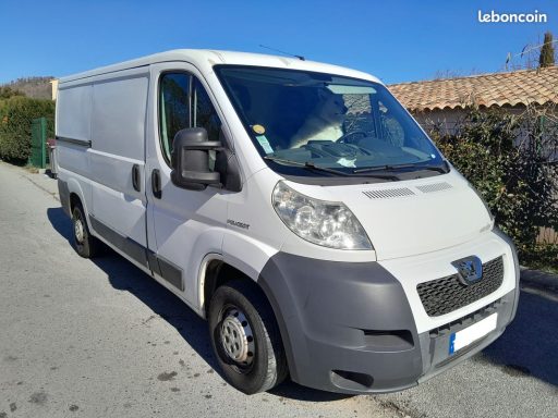 boxer Fourgon utilitaire blanc garé sur une route, avec des paysages environnants.