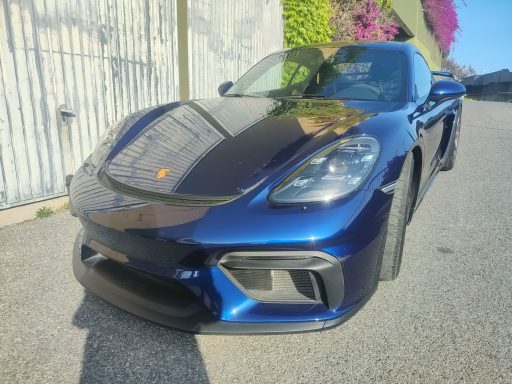 Porsche Cayman Voiture sportive bleue avec un design élégant, stationnée sur une route.